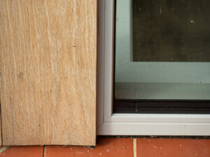 Fixed window installed on a red tile cill with black compriband weather seal and oak clad post